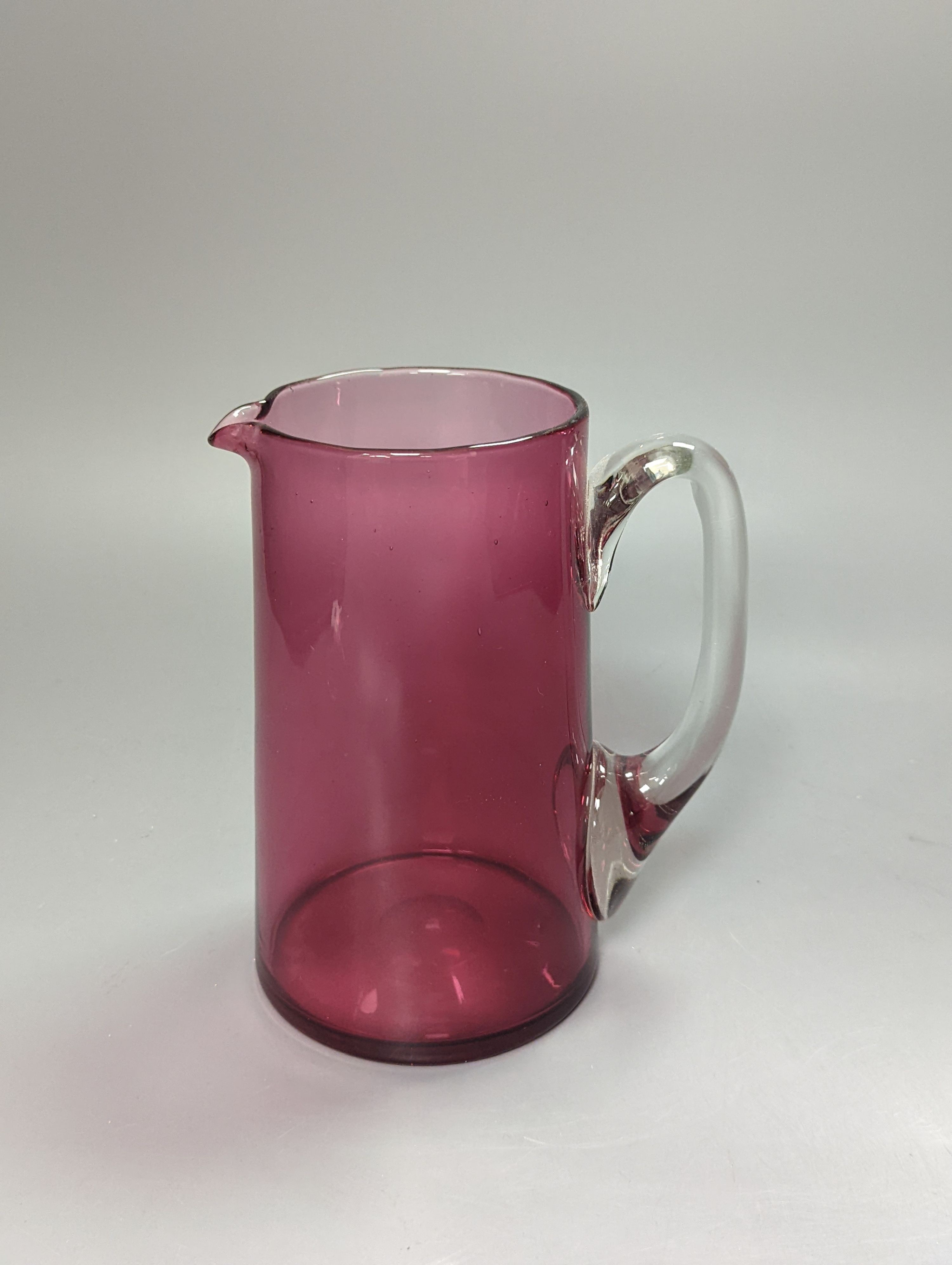 A pair of late Victorian cranberry glass frill vases, height 23cm, and a similar tapering jug